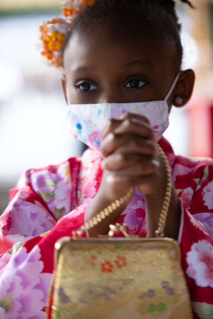 A little girl with dreadlocks and a face mask, in a pink shirt, holding her clutch purse' strip - Tokyo Portrait Photographer